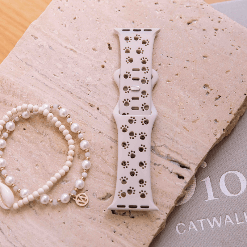 Pink animal print Apple Watch band worn on wrist with bracelets
