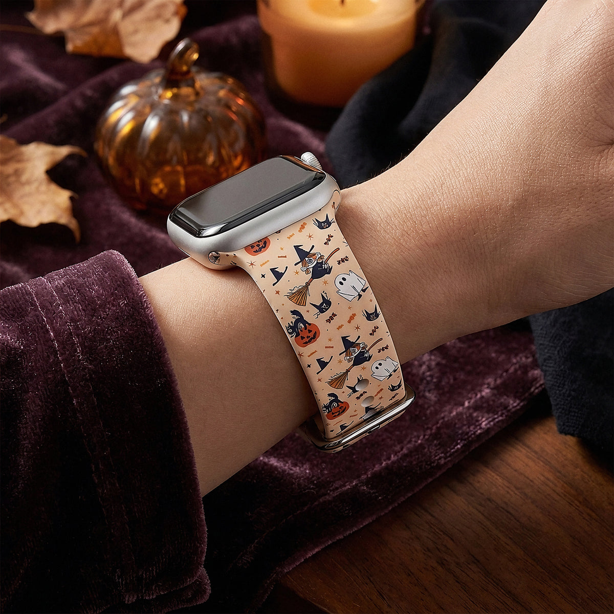 Trick or Treat Halloween Apple Watch band on a wrist next to a glass pumpkin and candle